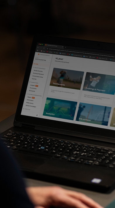 Person viewing a laptop screen displaying a website with Trackman Booking & Payments