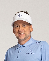 Ian Poulter in a light blue polo and white visor, smiling against a neutral background.