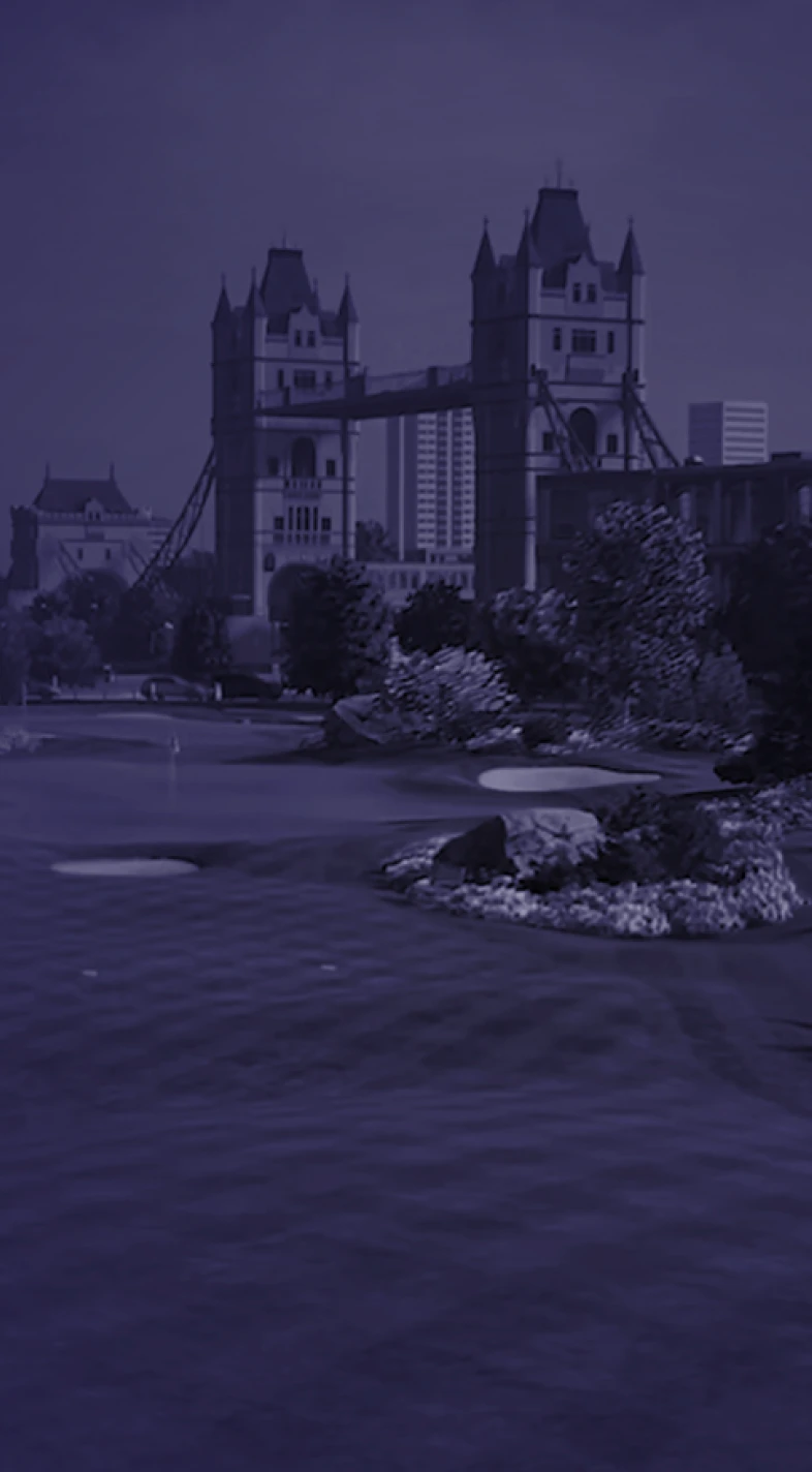A riverside view of a bridge with tall towers, surrounded by trees and city buildings, under a dusky, purple-tinted sky.